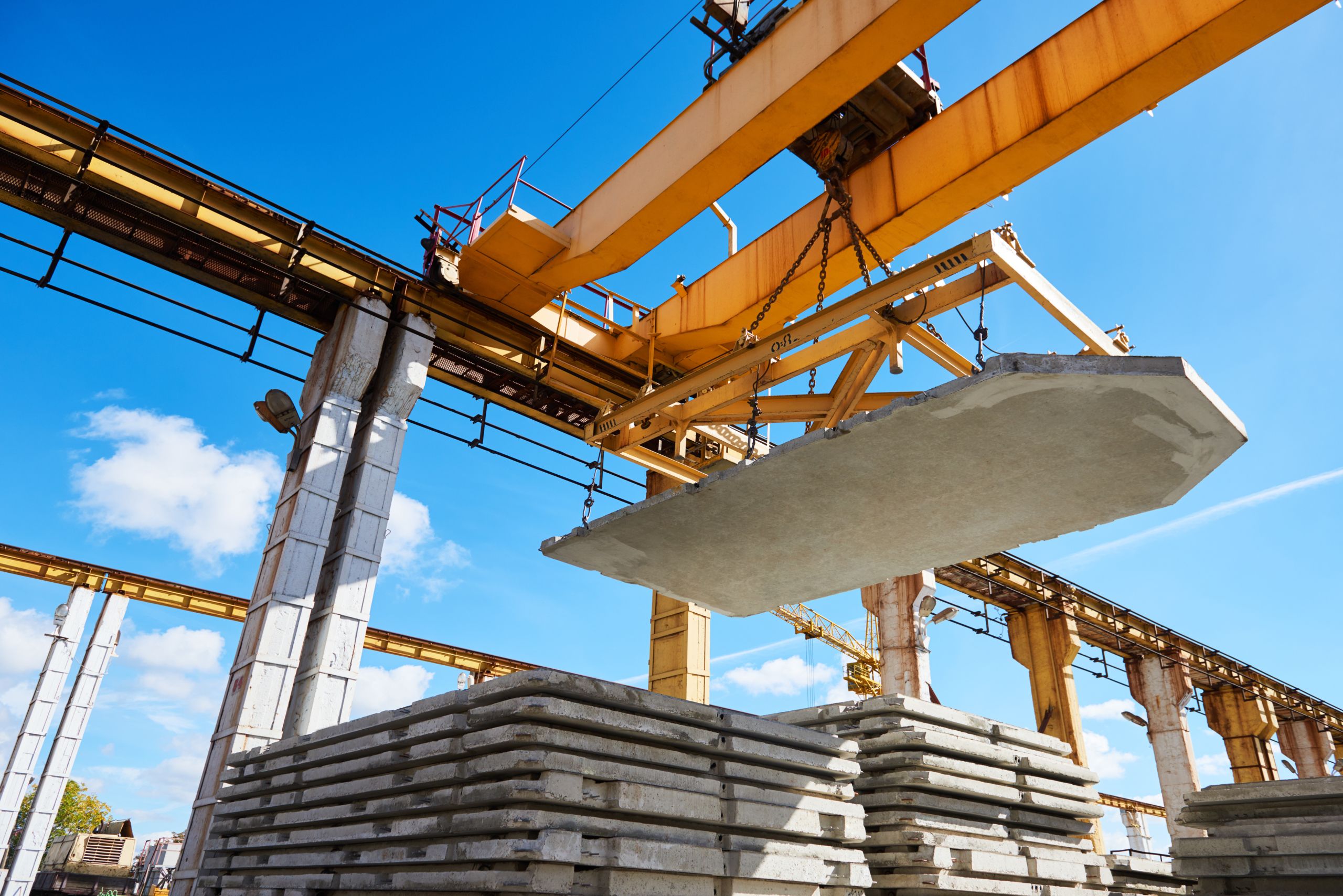 Construction industry. Gantry crane hoisting of concrete slab at factory